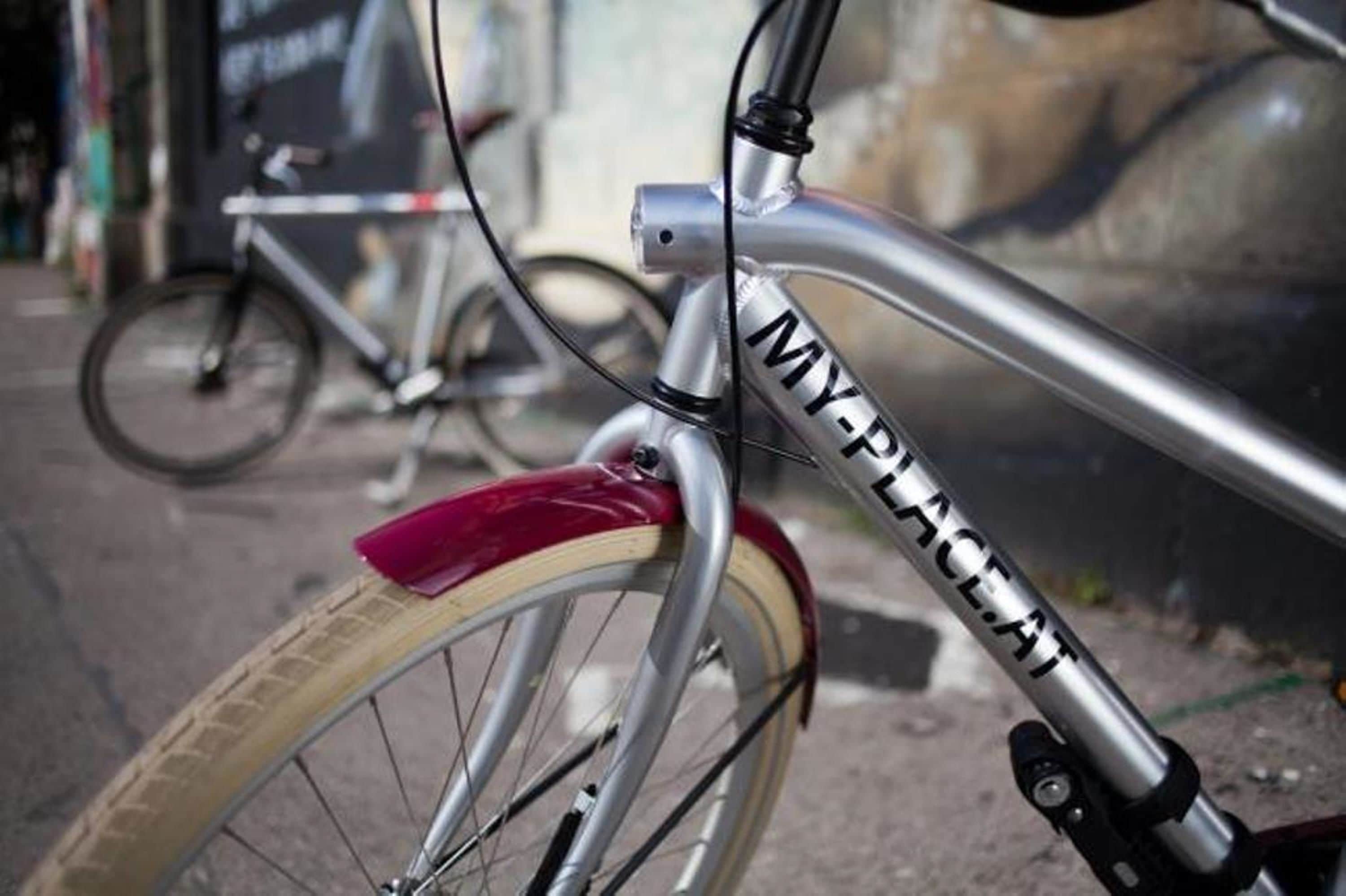 A close-up of a bicycle with the text "MY-PLACE-AT" on the frame.