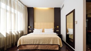 A hotel room with a large bed, a mirror, and a view of the hallway.
