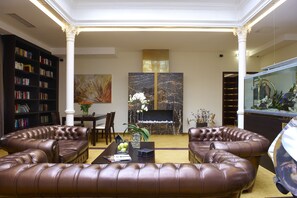 A living room with leather sofas, a fireplace, a bookshelf, and a fish tank. - MyPlace Premium Apartments (Vienna)