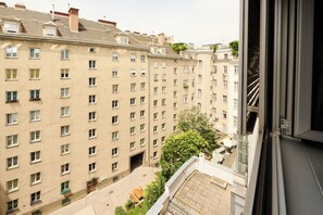 A high-rise building with multiple windows and balconies, a courtyard with outdoor furniture, and a view of adjacent buildings. - MyPlace Premium Apartments (Vienna)