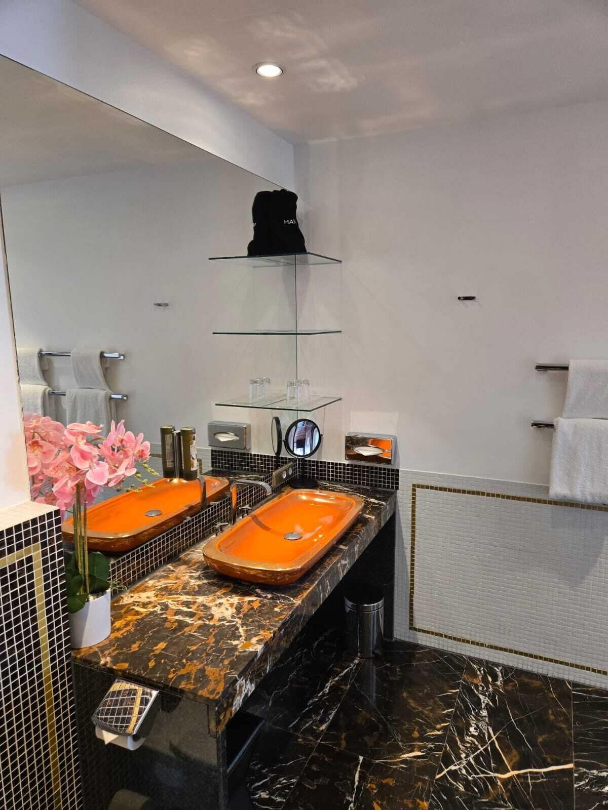 A modern bathroom with two sinks, a large mirror, and a towel rack.