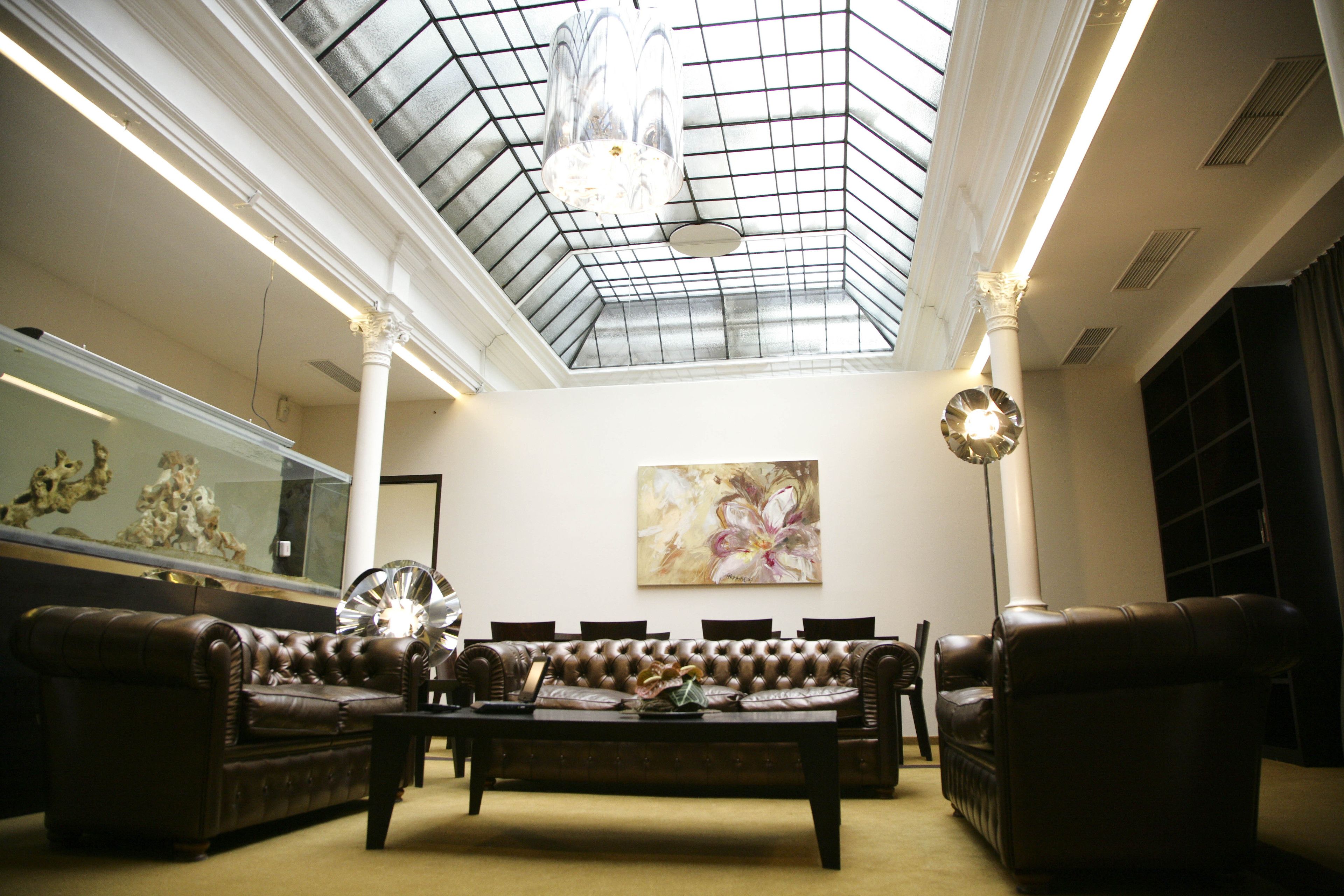 Un salon spacieux avec un plafond haut, une verrière et un grand tableau accroché au mur.
