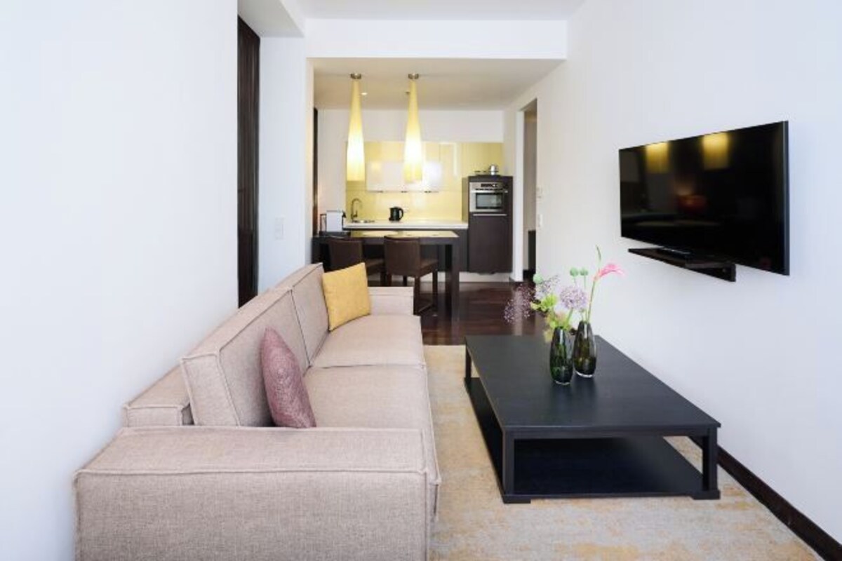 A modern living room with a sofa, a coffee table, and a flat-screen TV mounted on the wall.