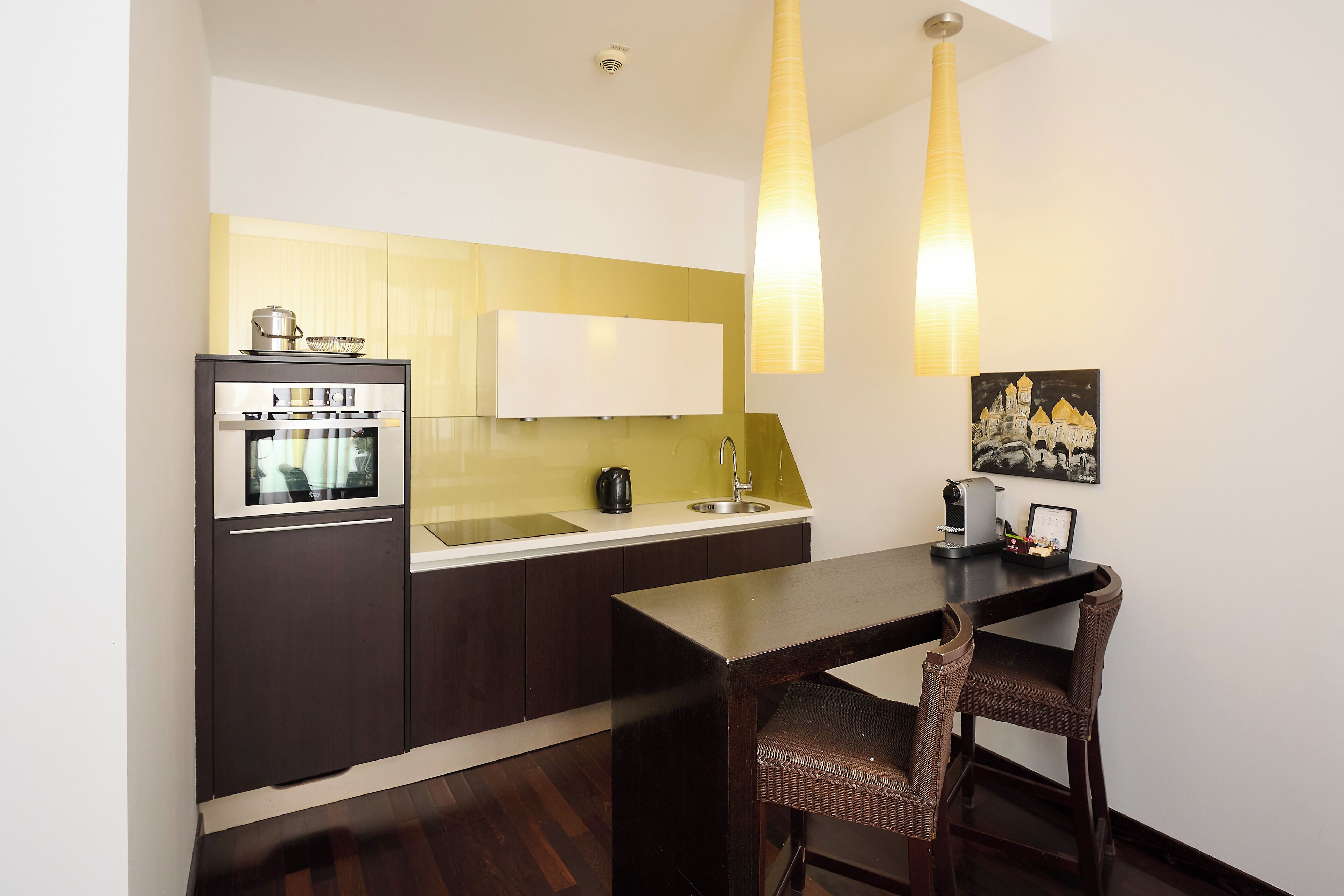 A compact kitchen with a built-in oven, a sink, and a dining area with a table and chairs.