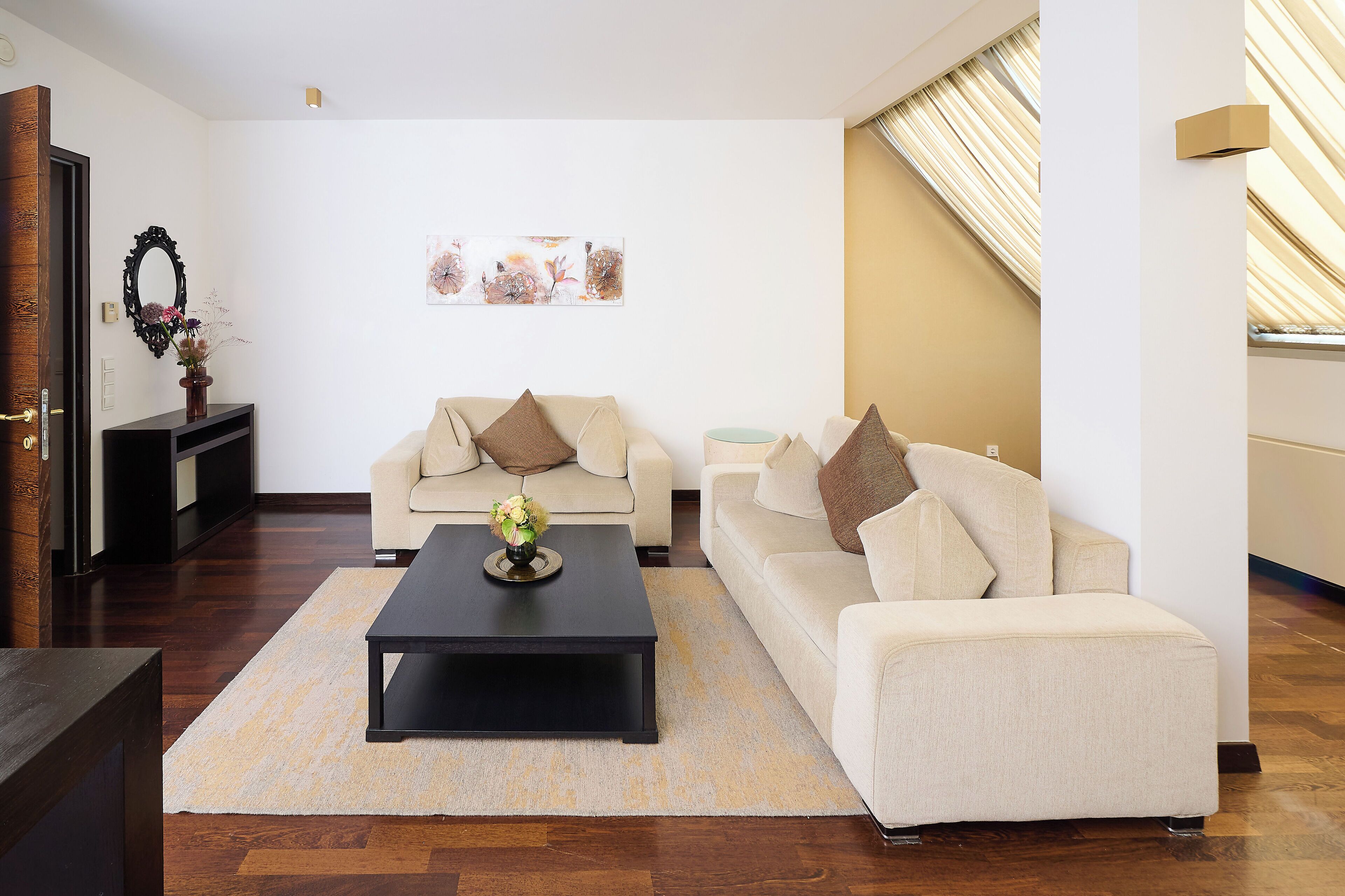 Uma sala de estar com sofá, mesa de centro e espelho decorativo.