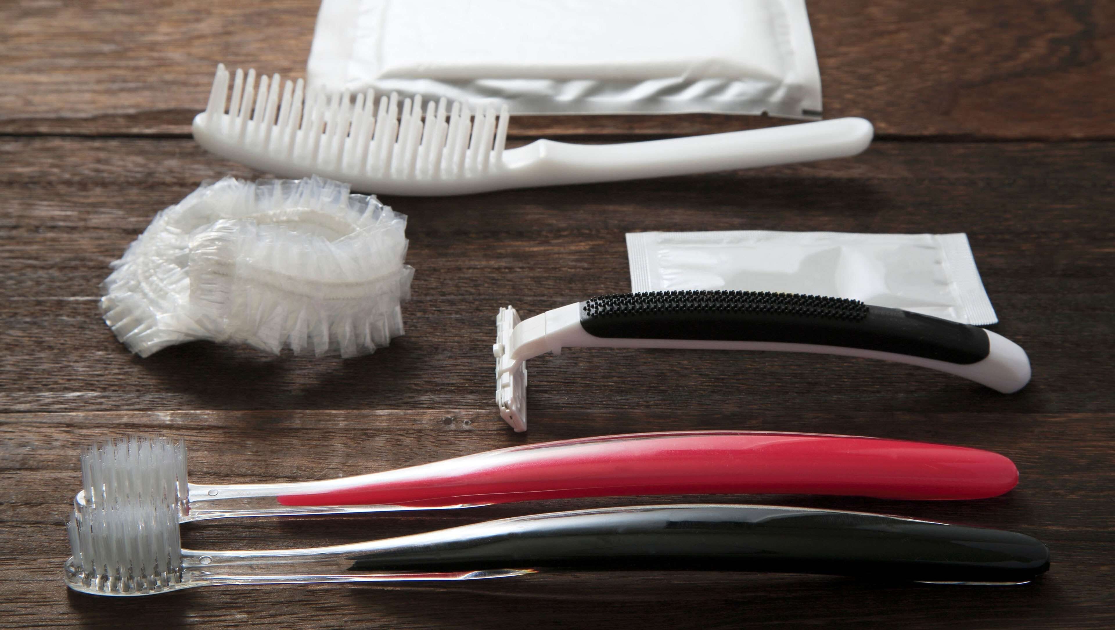 A set of grooming tools including a white toothbrush, a black and white toothbrush, a red toothbrush, and a white and black toothbrush on a wooden surface.