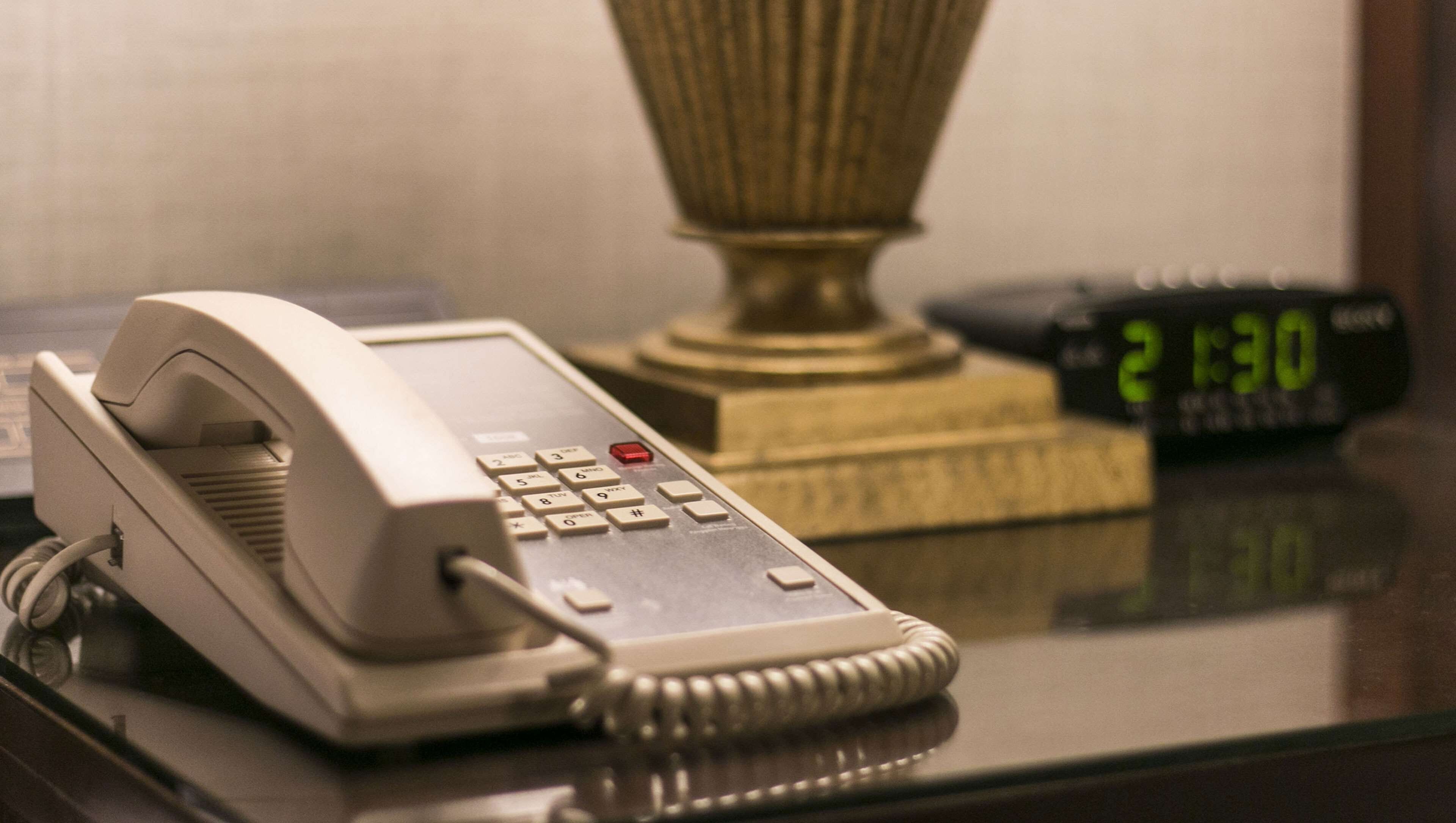 A telephone on a desk with a digital clock displaying 21:30.