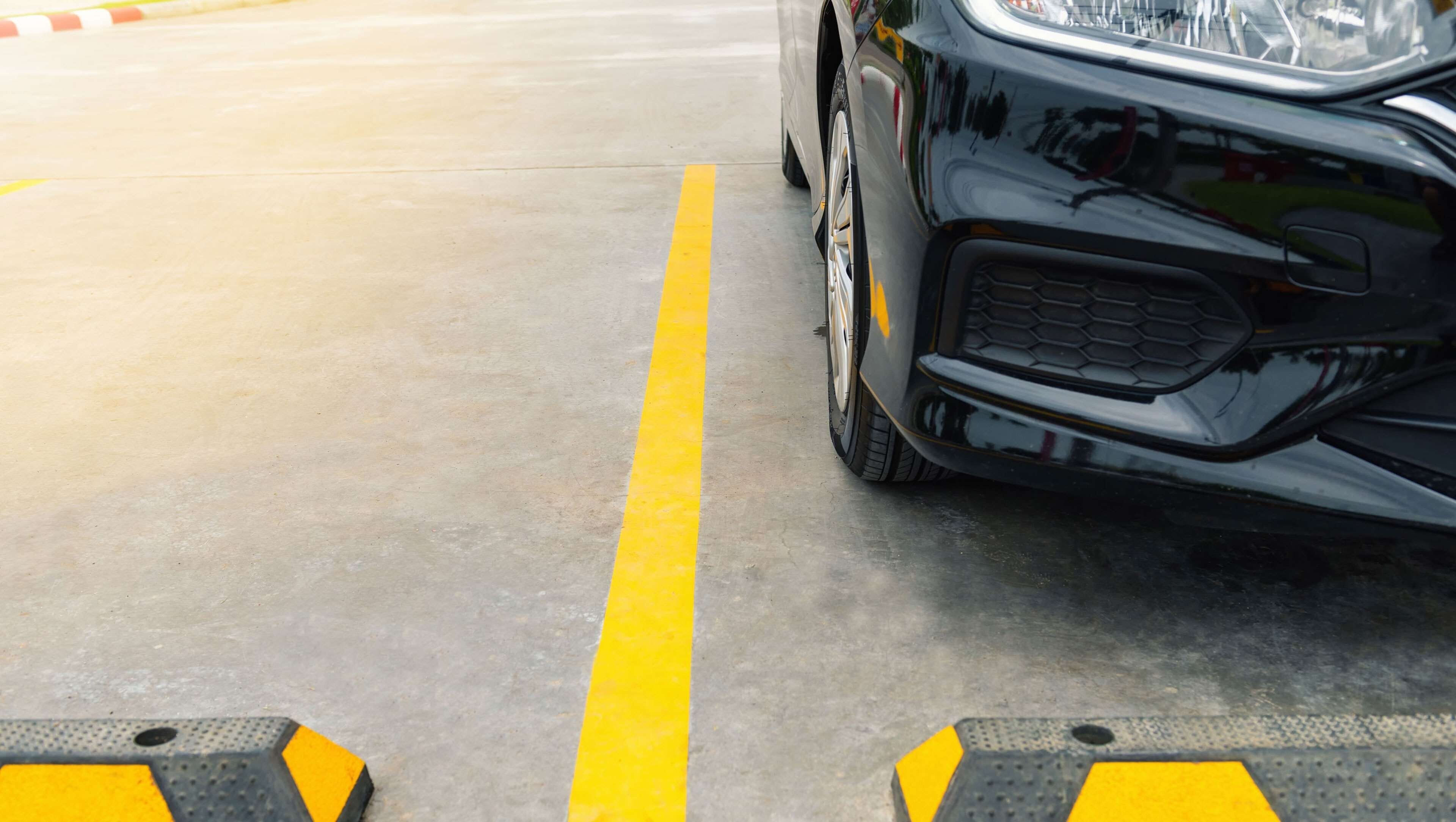 A car parked in a parking lot with yellow lines and bollards.