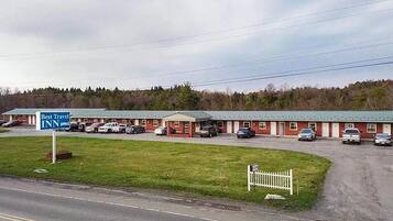 A Best Travel Inn with a row of single-story buildings, a parking lot, and a grassy area in front.