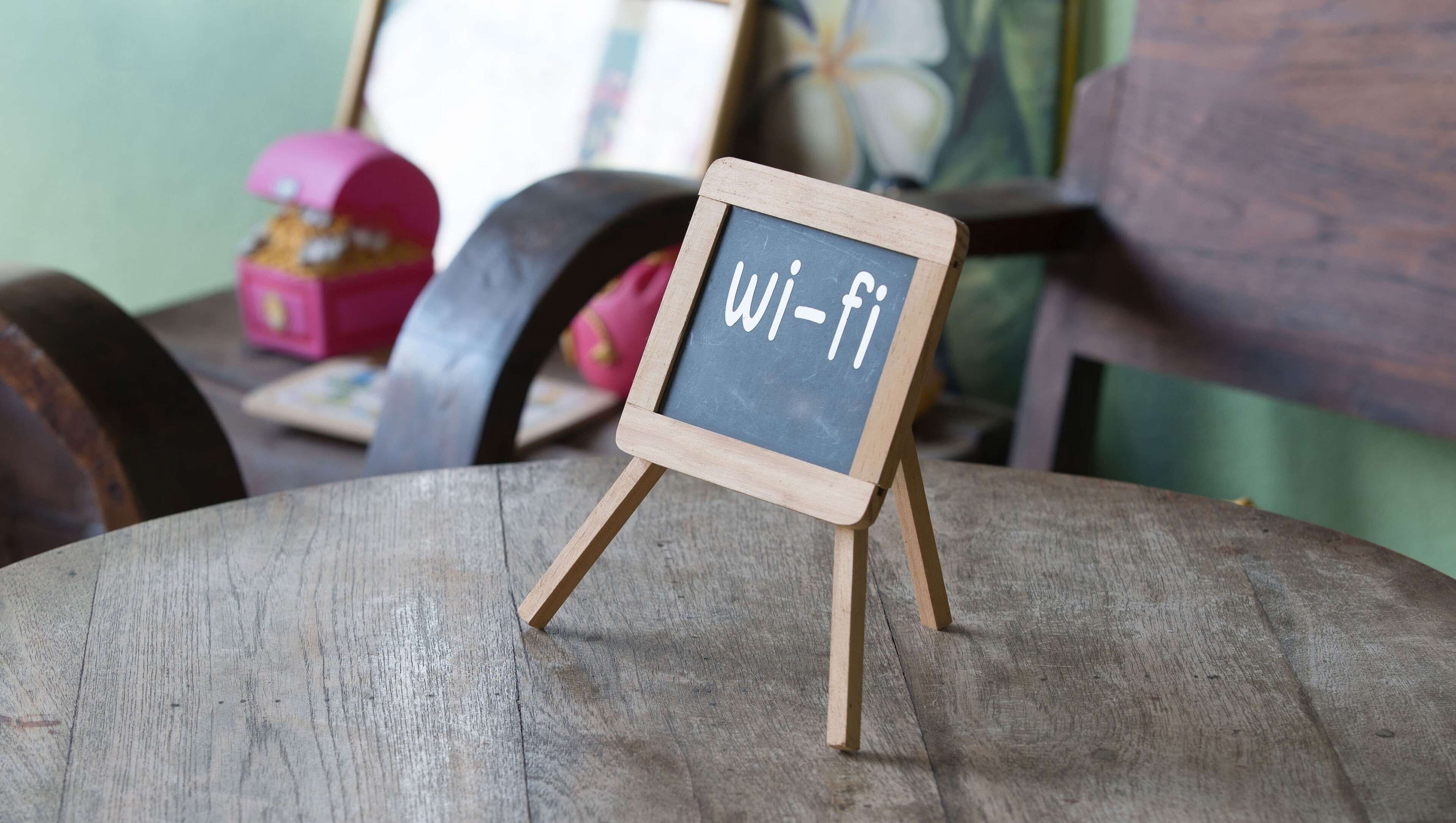 Un caballete de madera pequeño con una pizarra que muestra la palabra "wi-fi" en letras blancas.