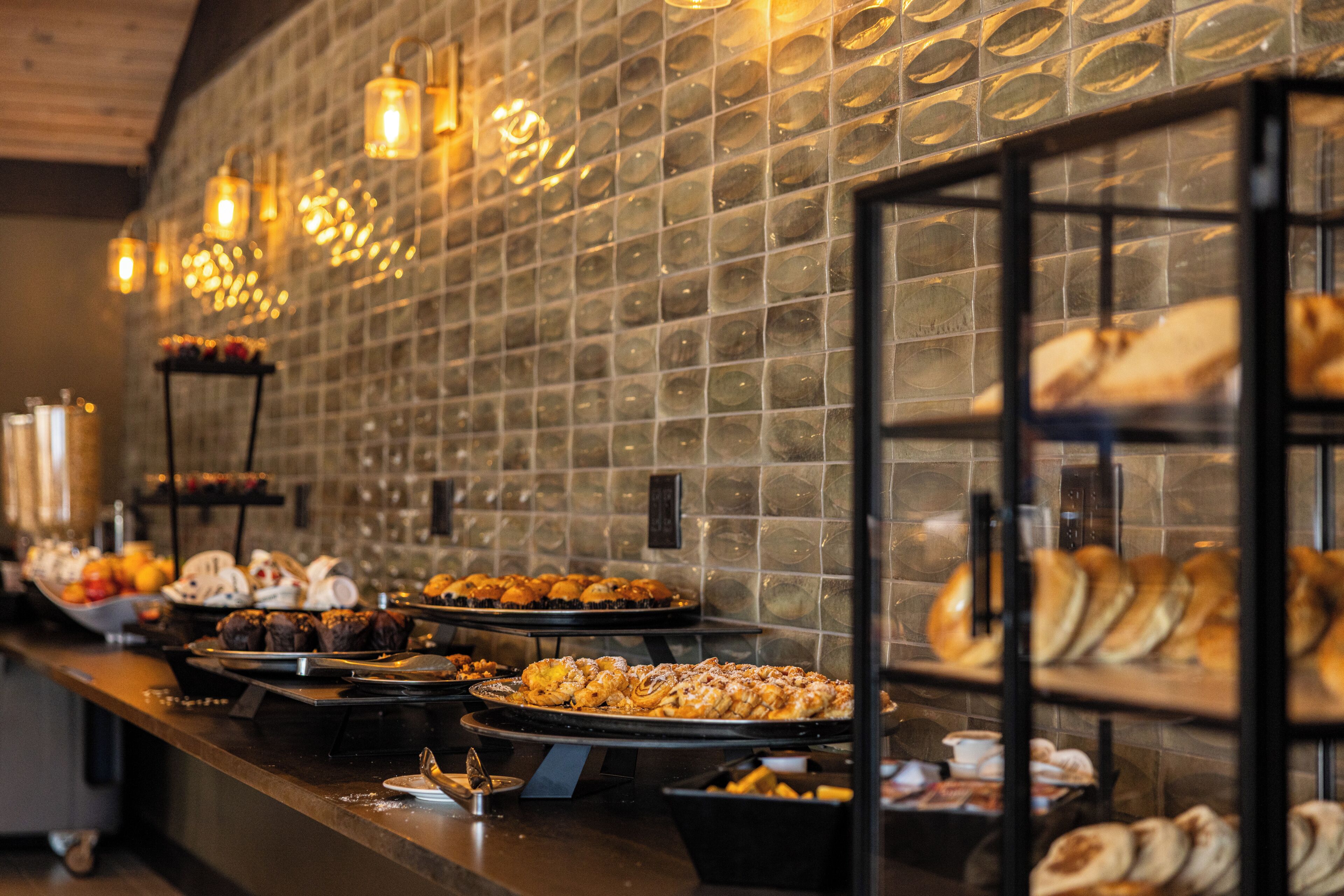 A buffet with various food items and a tiled wall in the background.