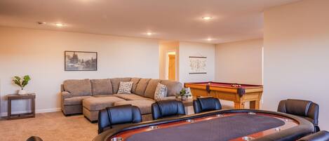 A room with a pool table, a sofa, and a billiards table.