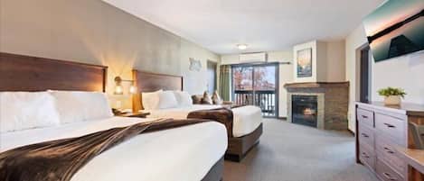 A hotel room with two beds, a fireplace, a TV, and a balcony.