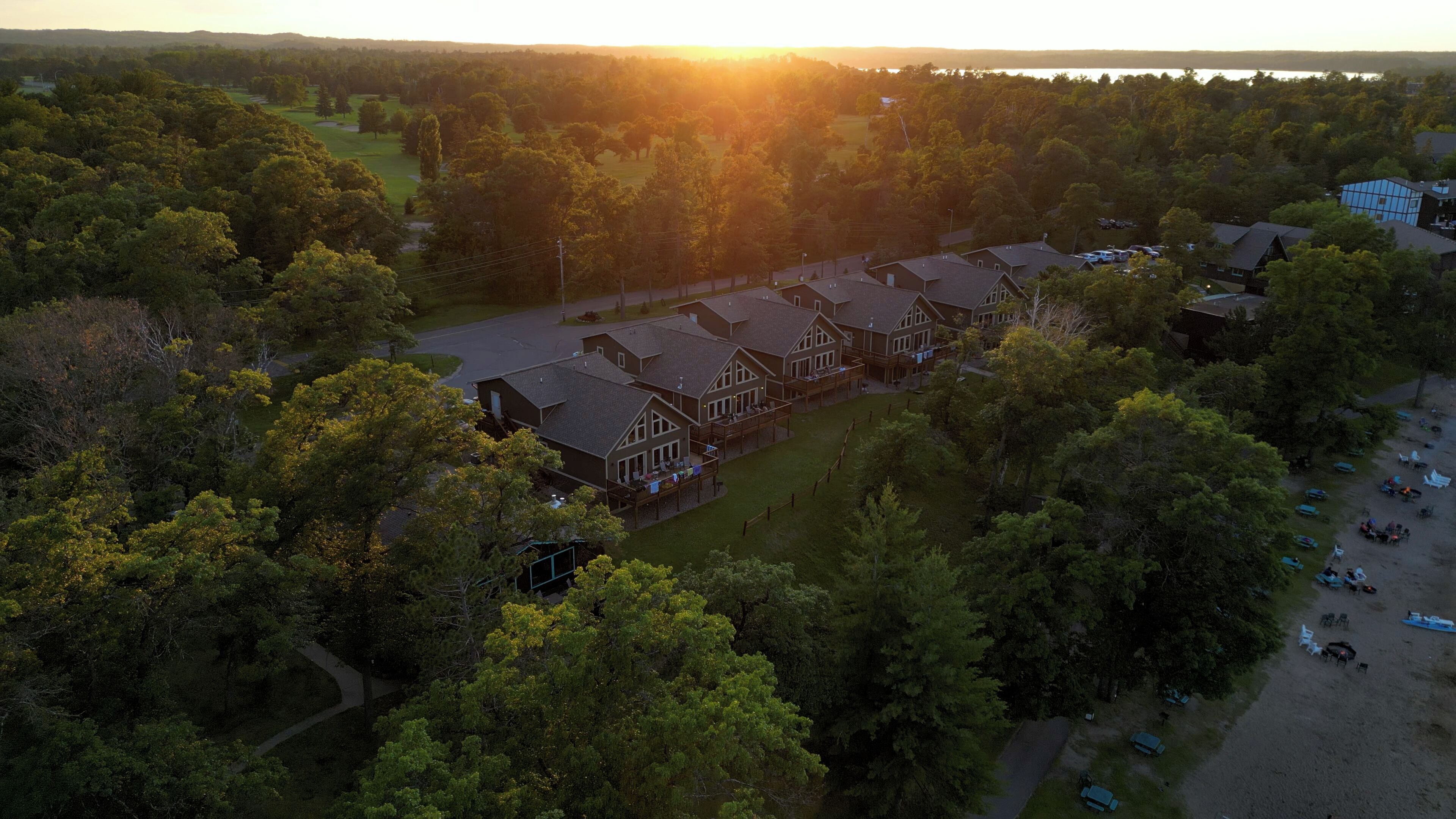 A large, multi-story building with a traditional architectural style, surrounded by dense trees and a golf course.