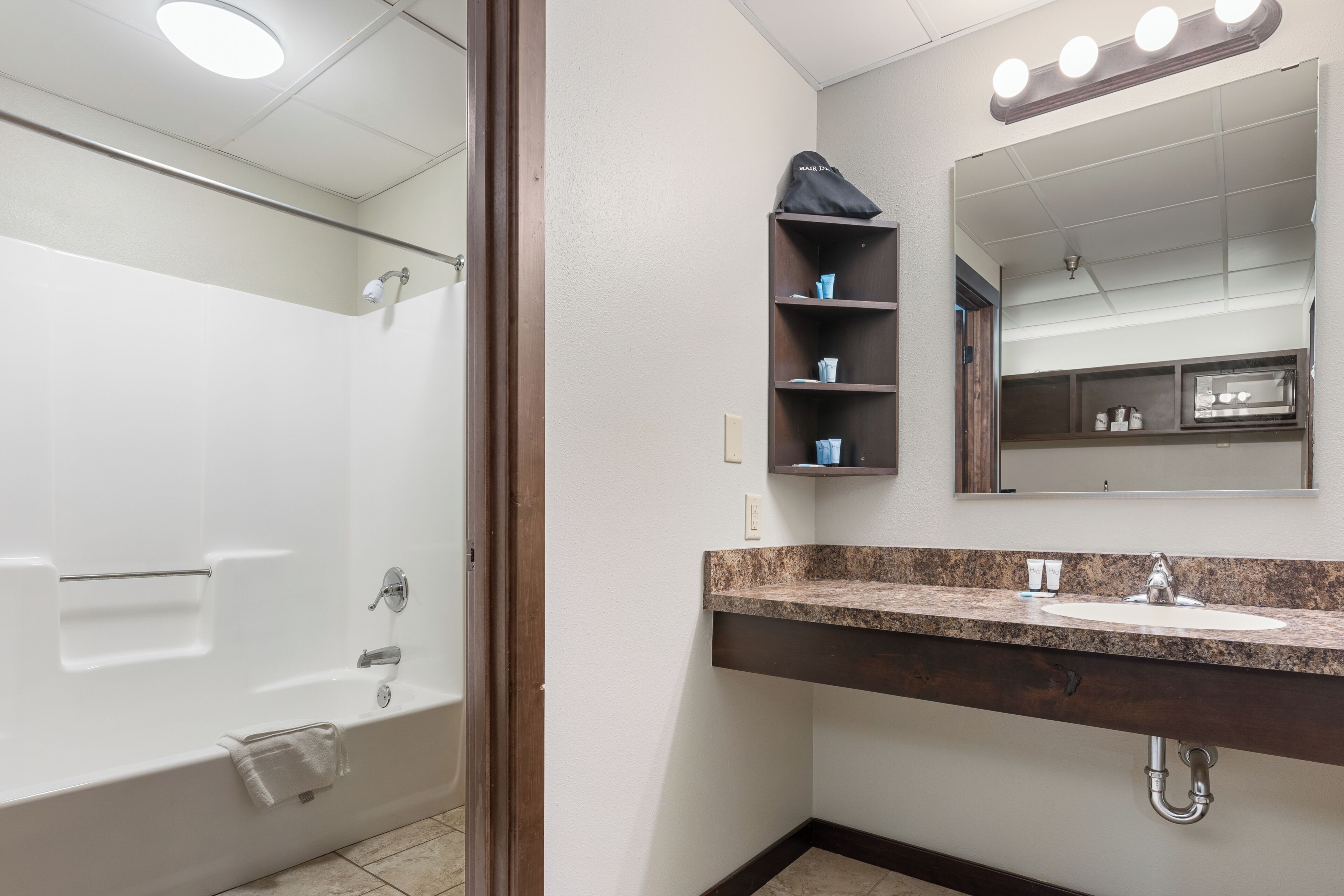 Une salle de bain avec une baignoire, un meuble-lavabo avec un miroir et des étagères contenant des articles de toilette.