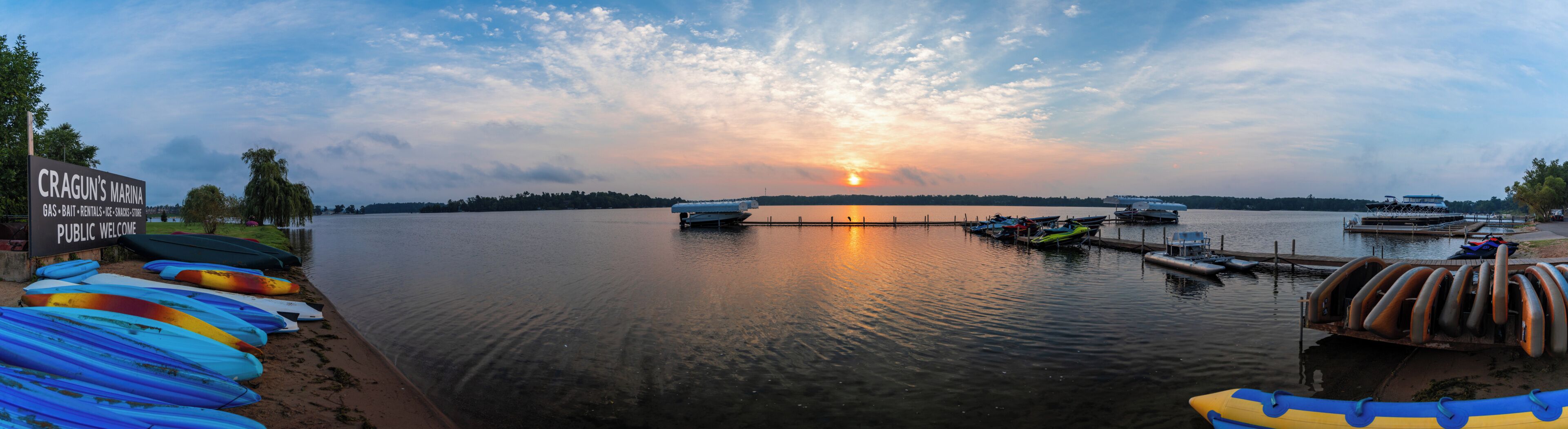 A marina with boats docked, a signboard for Cragun's Marina, and a sunset in the background.