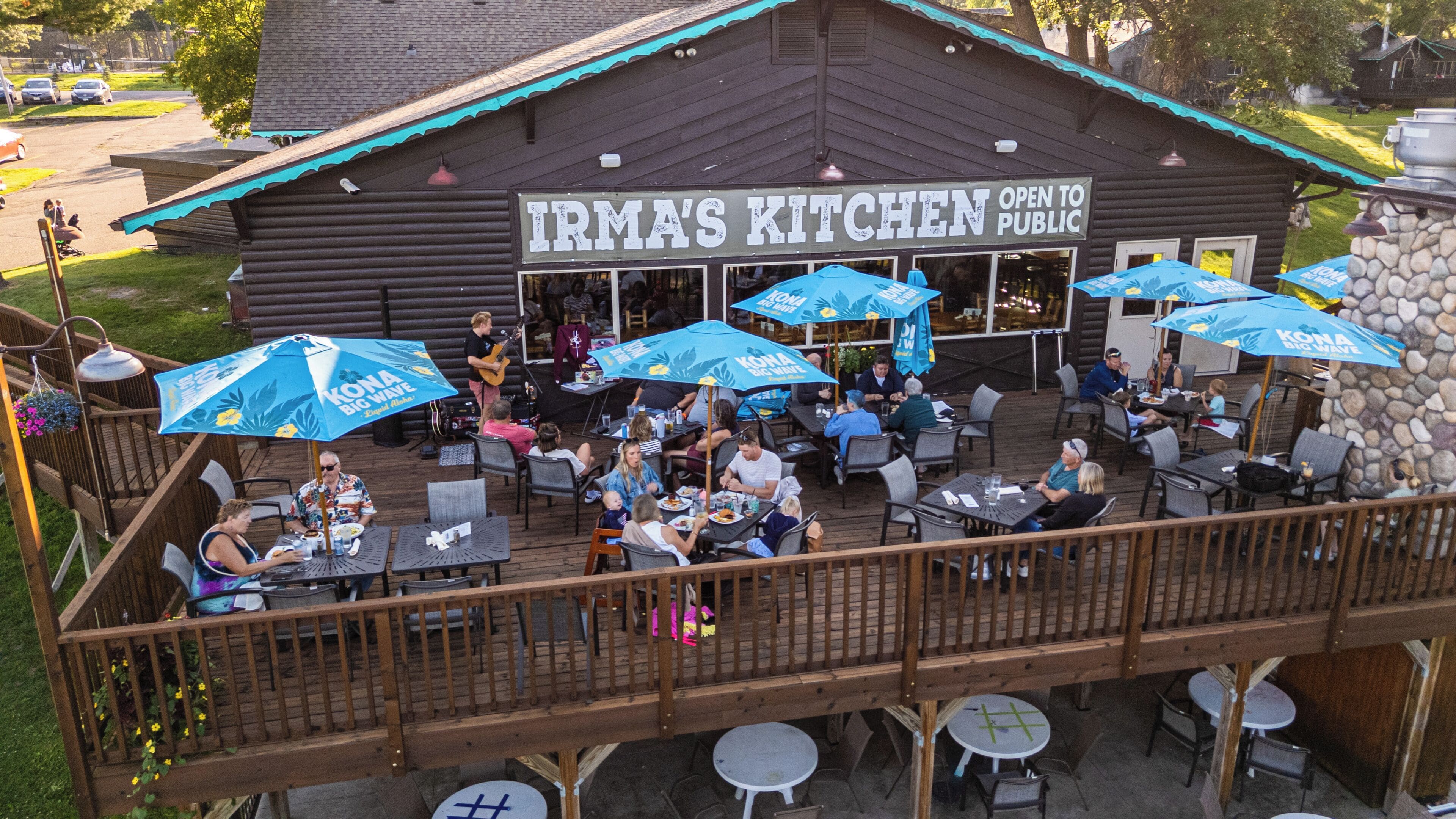 A restaurant with outdoor seating and a sign that reads 'IRMA'S KITCHEN OPEN TO PUBLIC.'