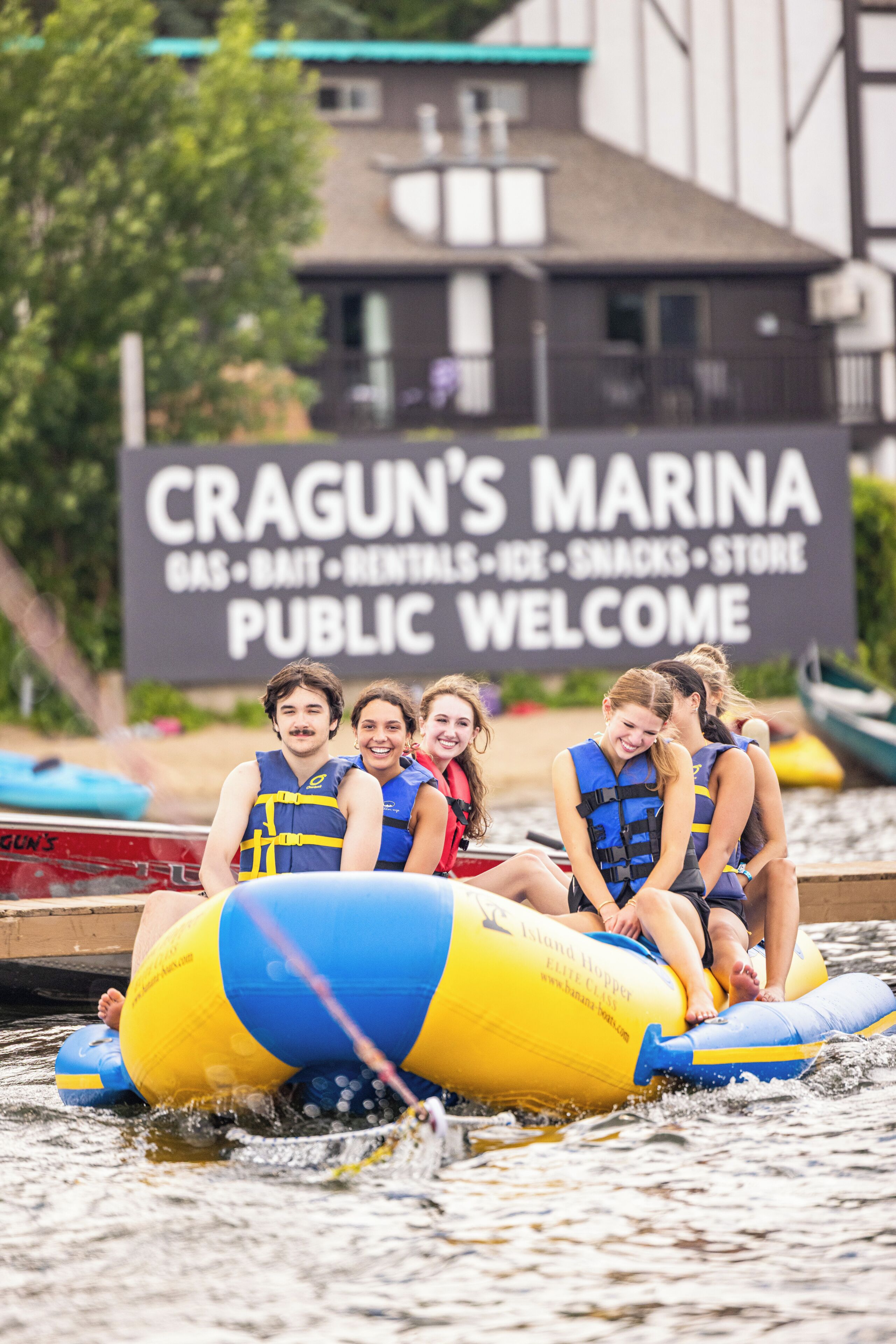 Un grupo de personas en una embarcación con un anuncio al fondo que promociona servicios de marina.