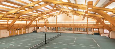 Een overdeelde tennisbaan met houten plafond en een net in het midden.