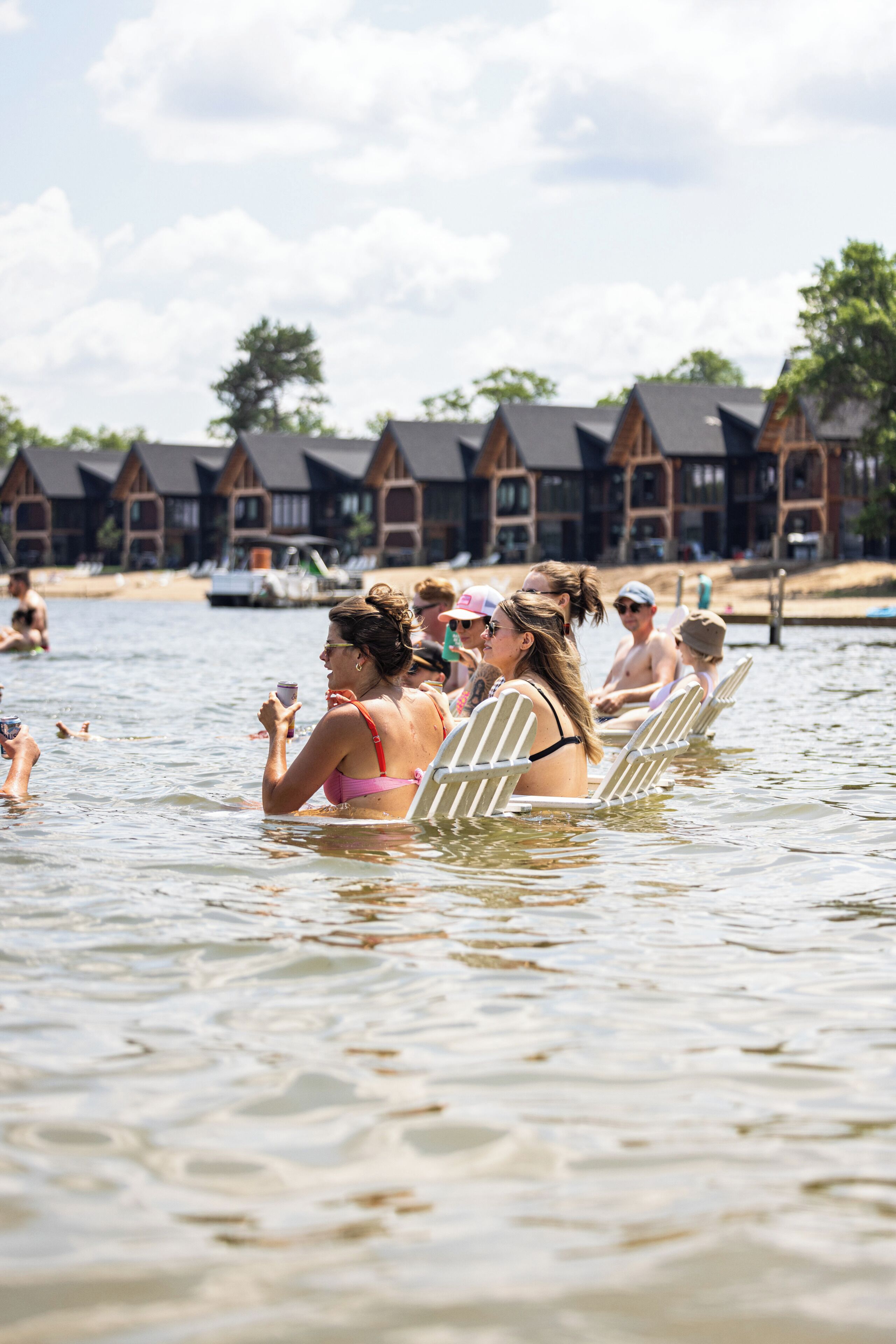 A group of people in a swimming area with wooden structures in the background.