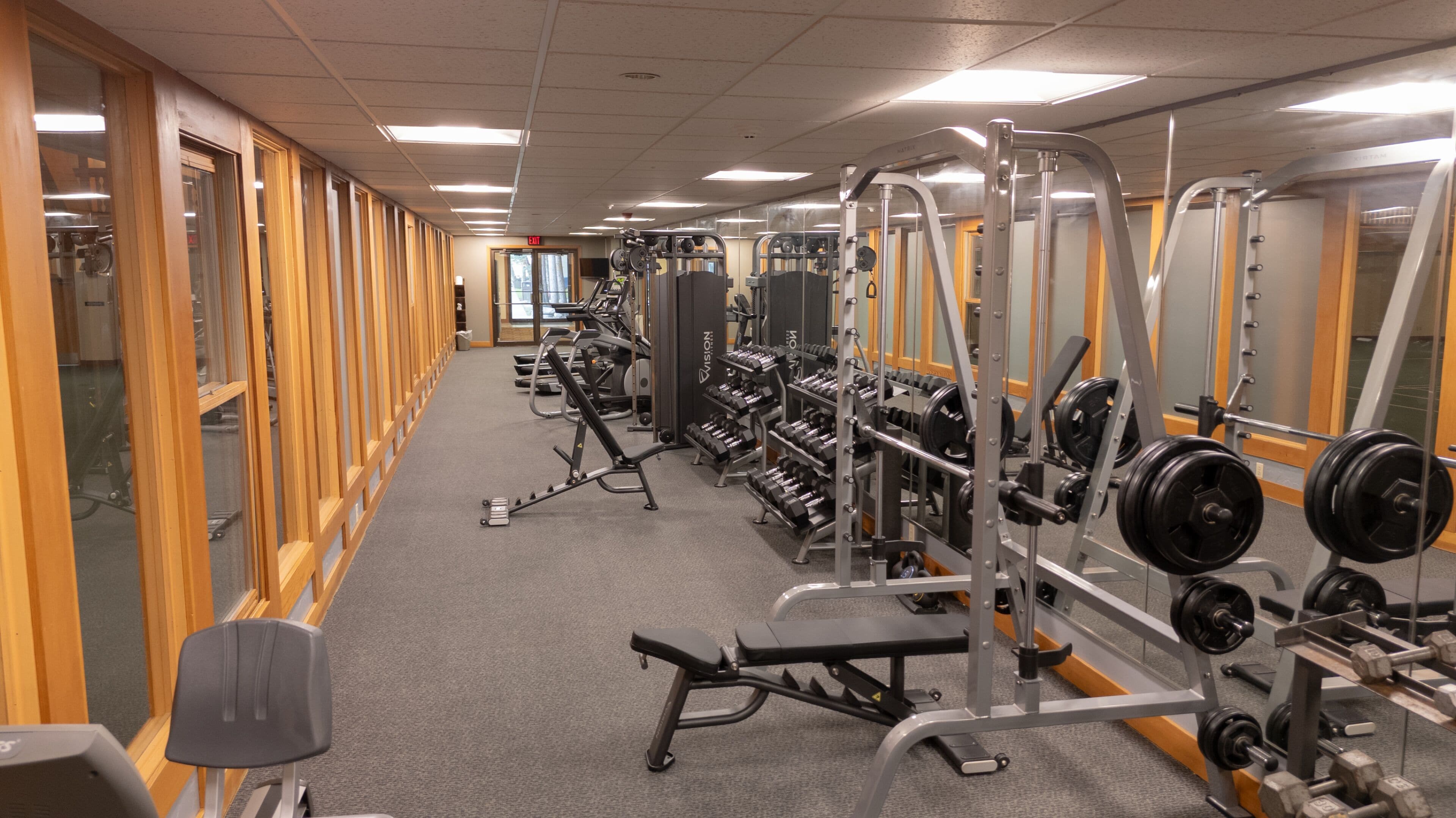 Une salle de sport équipée de divers appareils d’exercice, notamment des tapis de course, des appareils de musculation et des poids libres.