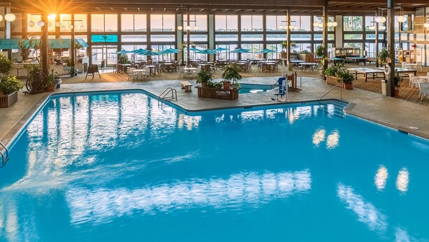 An indoor swimming pool with a view of the water outside.