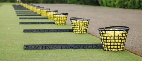 Een rij zwarte manden met de aanduiding 'CRAGUN'S LEGACY COURSE' op een groene ondergrond, met bomen op de achtergrond.