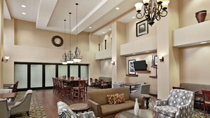 A spacious lobby with a dining area, sofas, armchairs, and a chandelier. - Hampton Inn & Suites Enid (Enid)