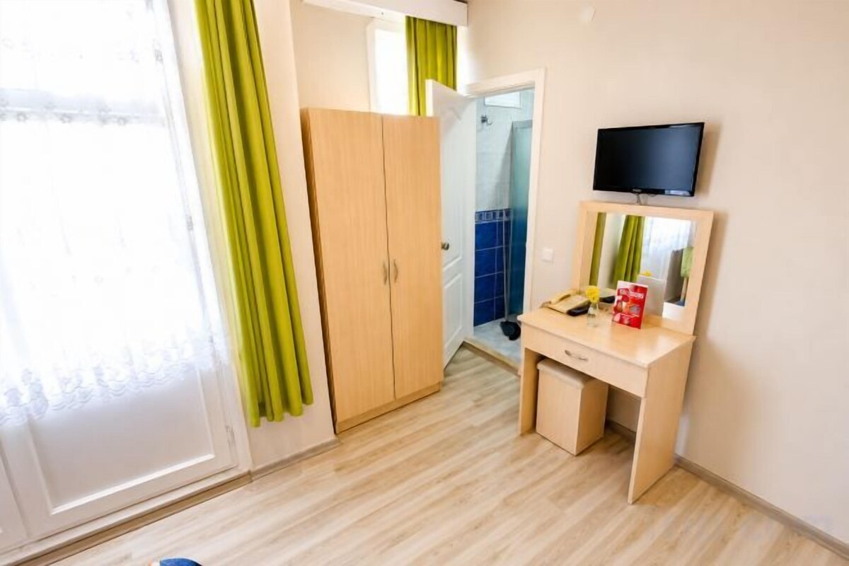 Une pièce comprenant un bureau en bois, une télévision, une armoire et une porte coulissante.