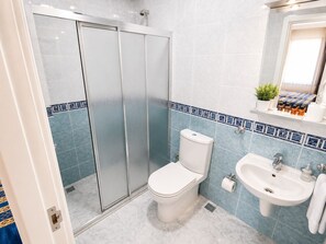 A bathroom with a glass-enclosed shower, a toilet, a sink, and a mirror. - Anadolu Hotel (Istanbul)