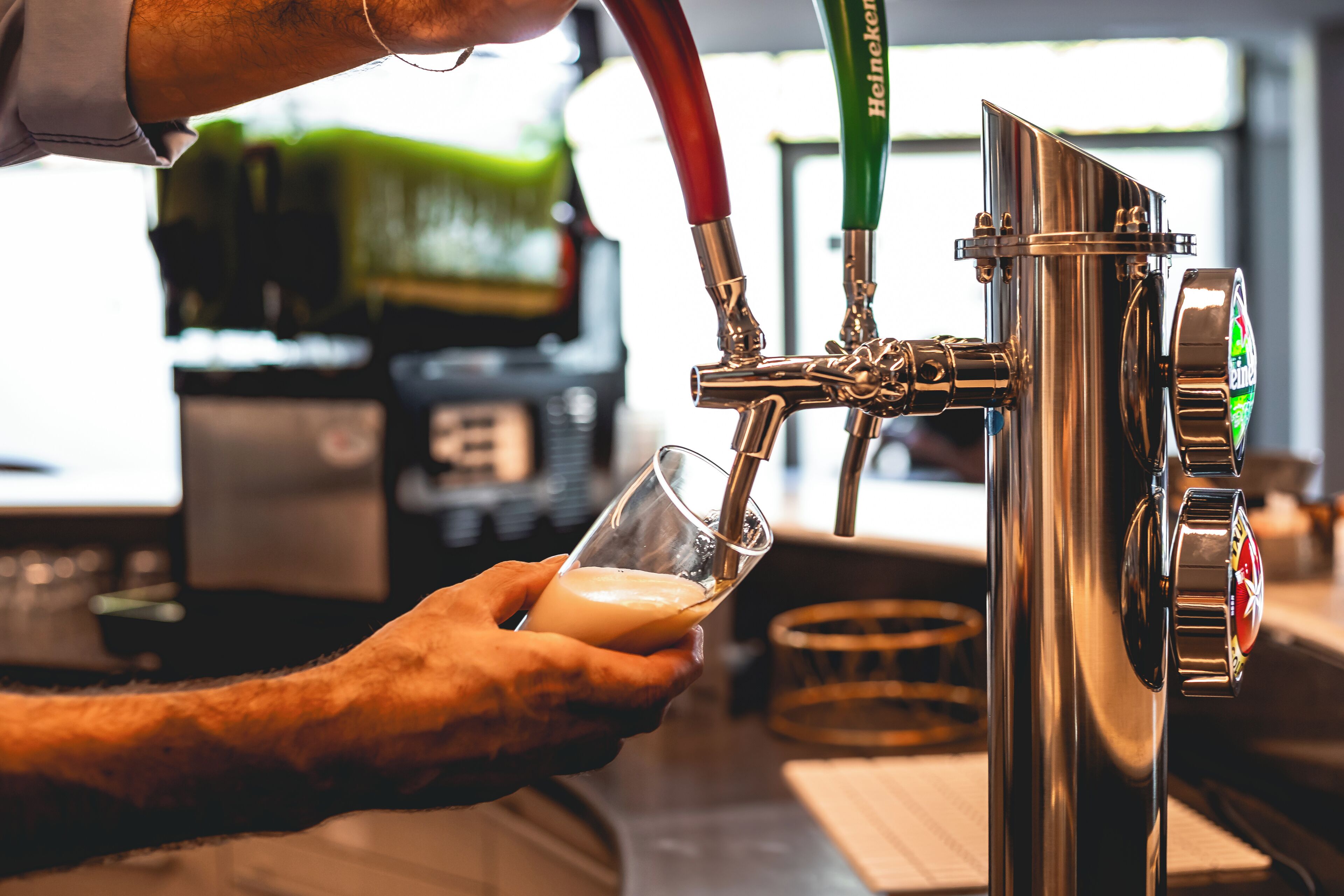 A hand holding a glass under a beer tap with a beer being dispensed.