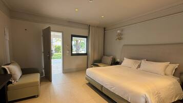 Quarto de hotel com cama, escrivaninha, cadeira, janela e porta.