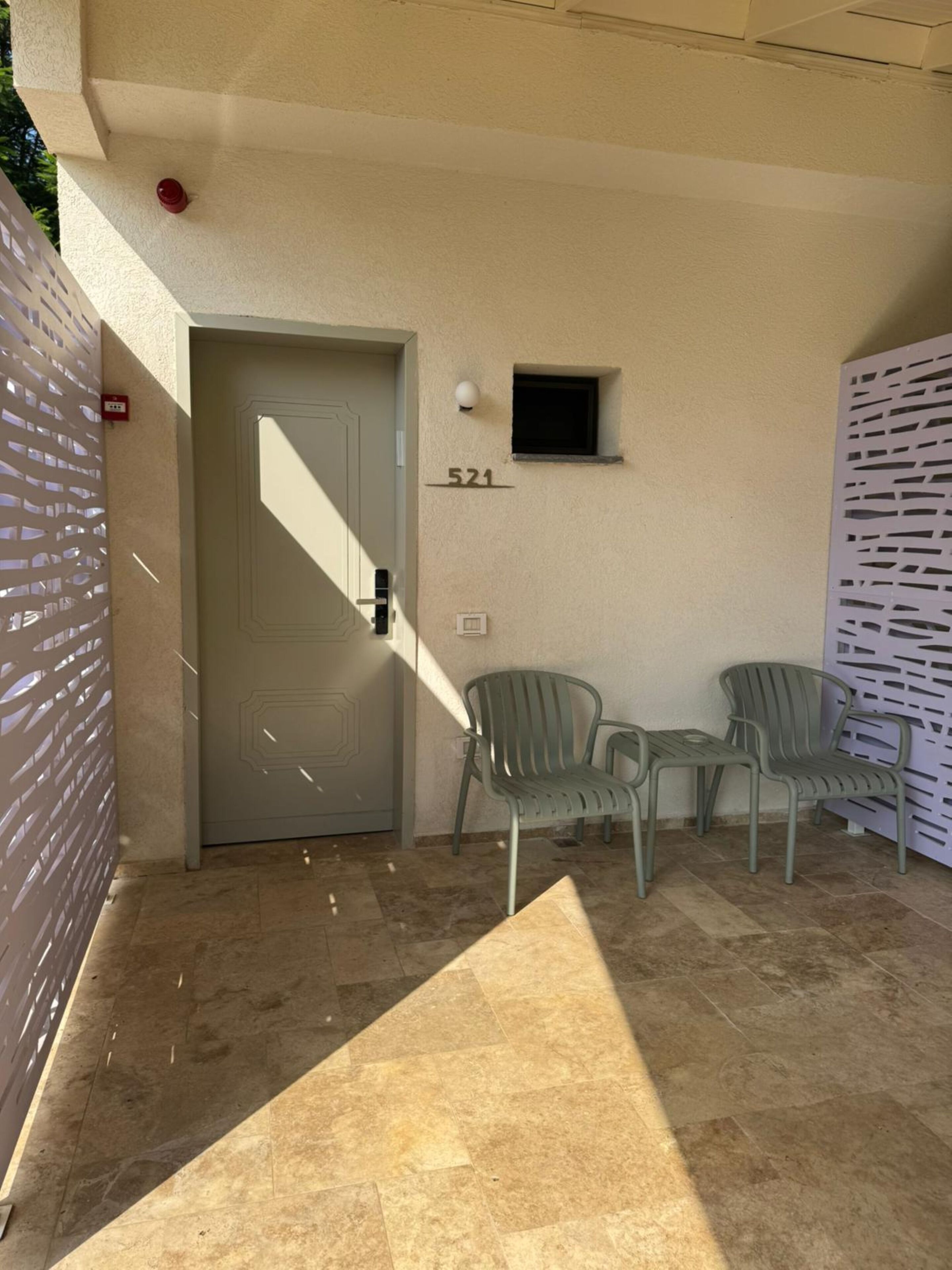Entrada de un edificio con puerta, una ventana pequeña y el número 521 en la pared.