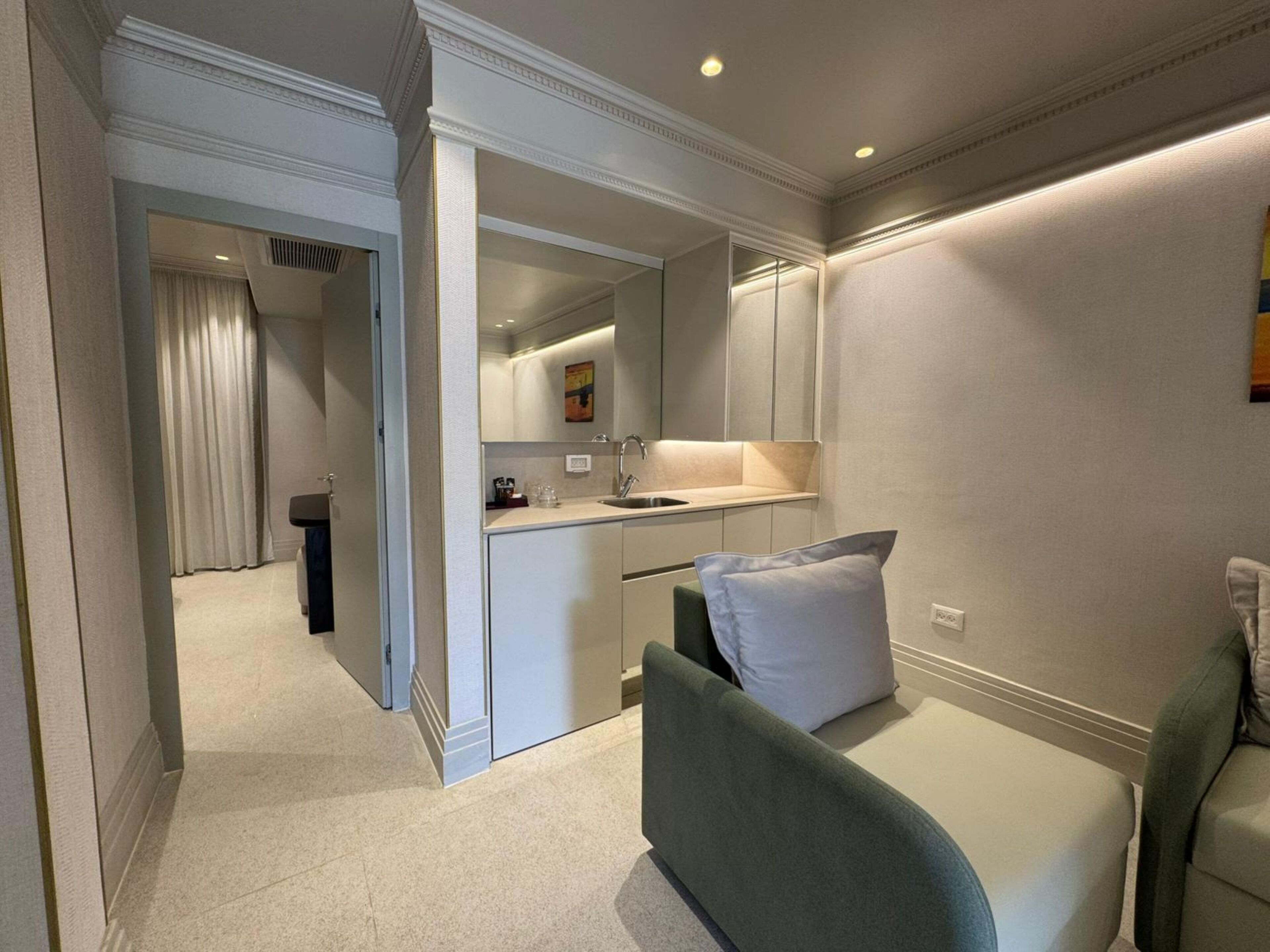 Una habitación de hotel moderna con kitchenette, un sofá con un cojín y un espejo.