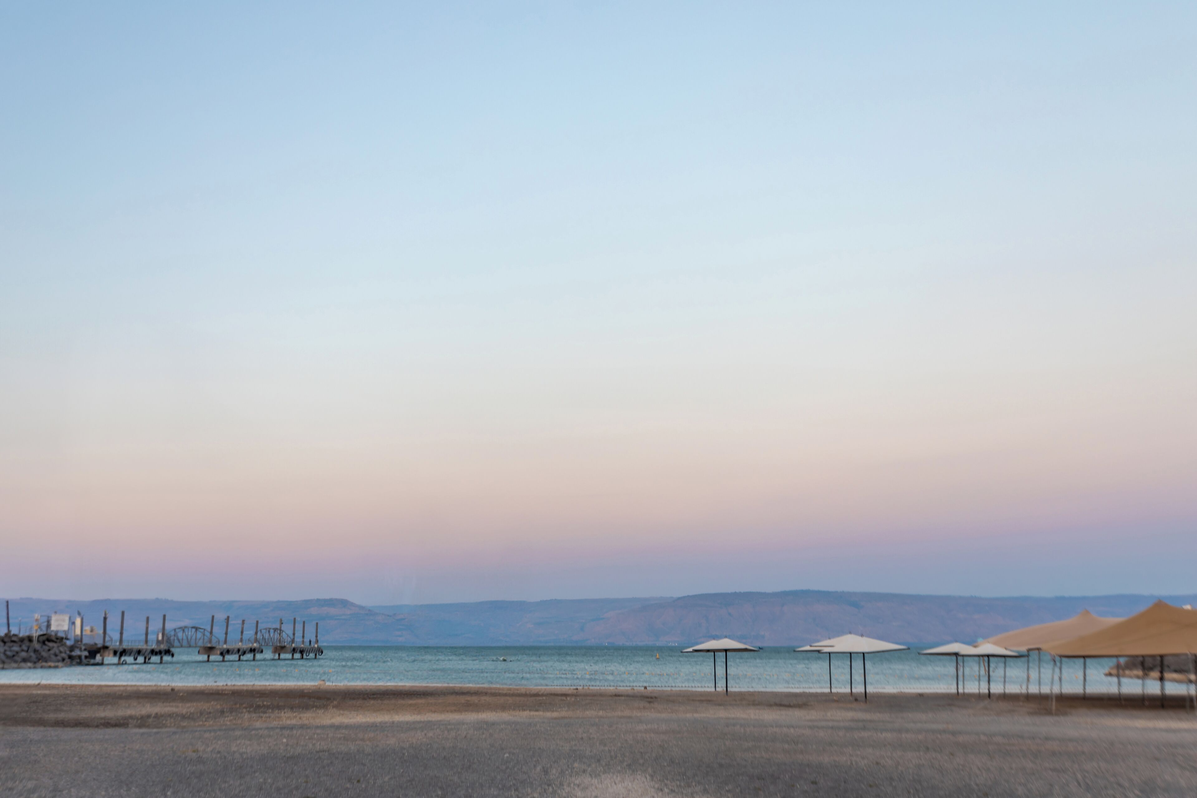 A beach with umbrellas and a clear sky.