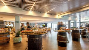 Un restaurante espacioso con barriles de madera como mesas, un diseño moderno de techo y vistas al exterior a través de amplias ventanas.