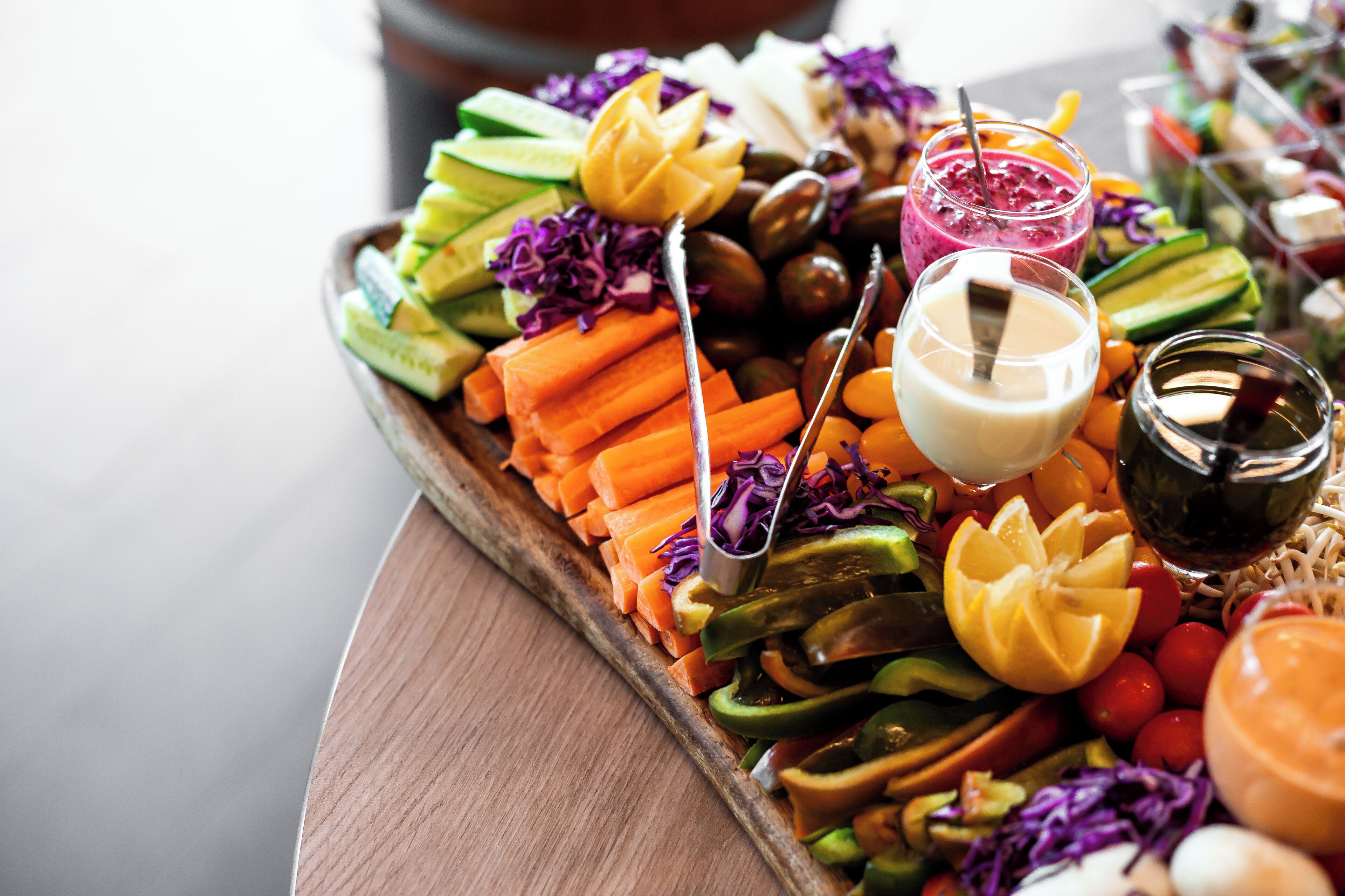 Una bandeja de madera llena de frutas, verduras y salsas.
