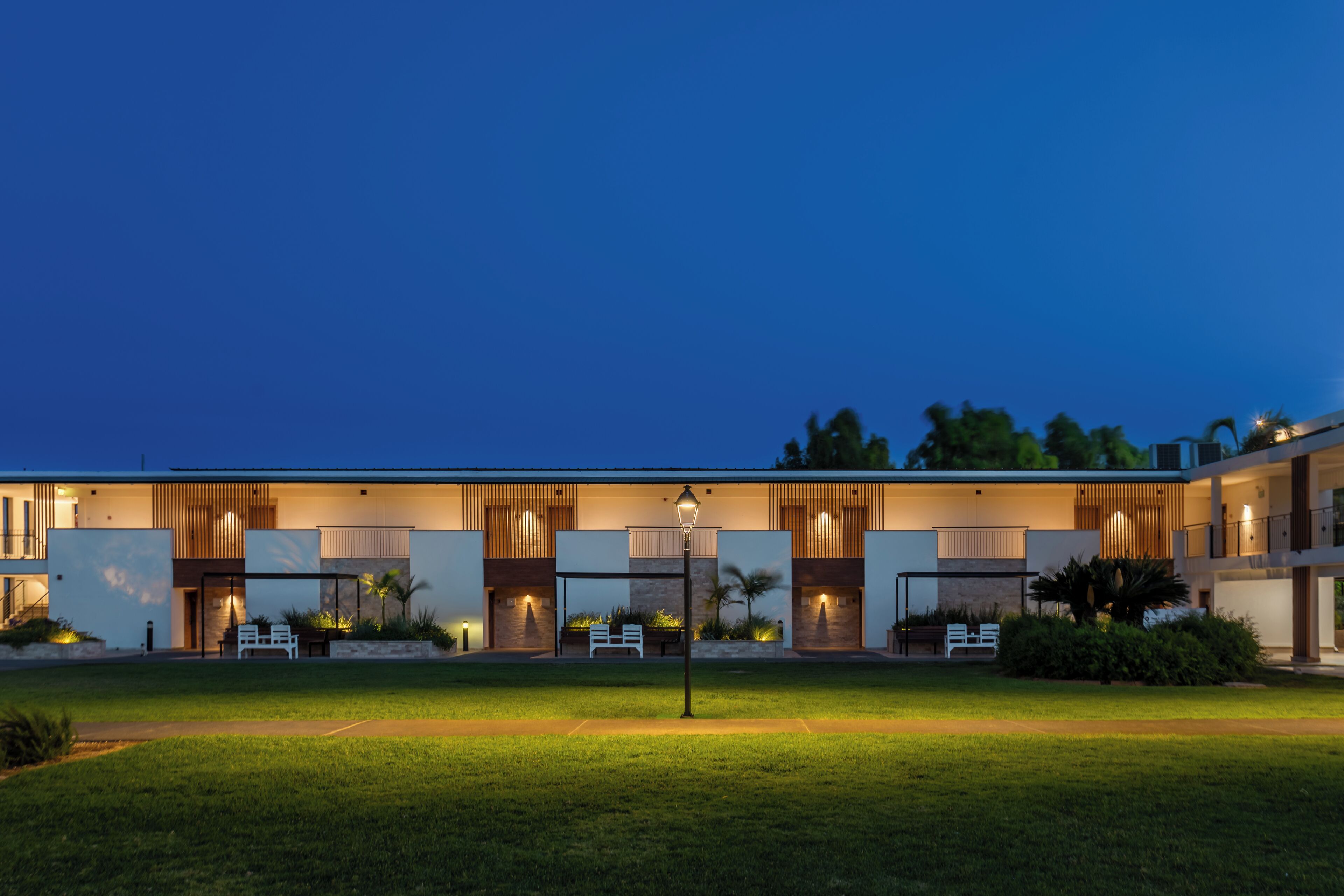 A modern hotel with a flat roof, large windows, and a well-lit entrance.