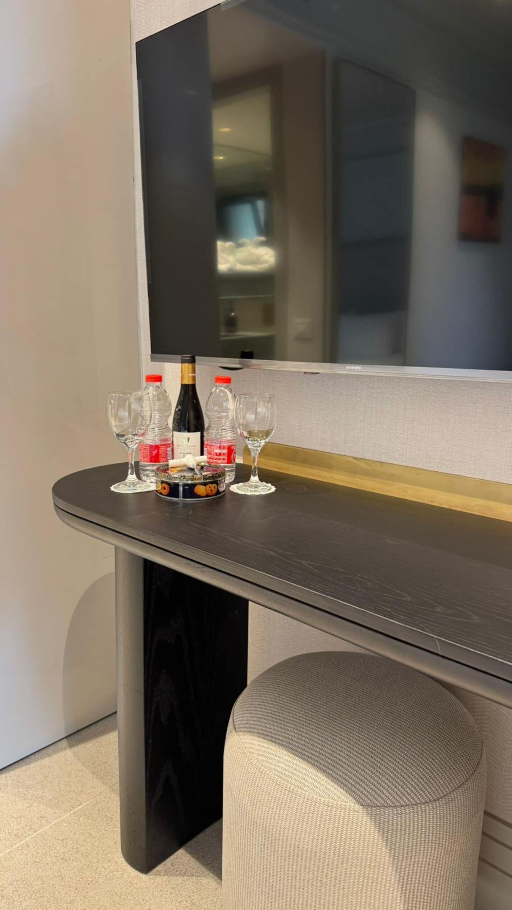 A table with a bottle of wine, glasses, and a fruit bowl.