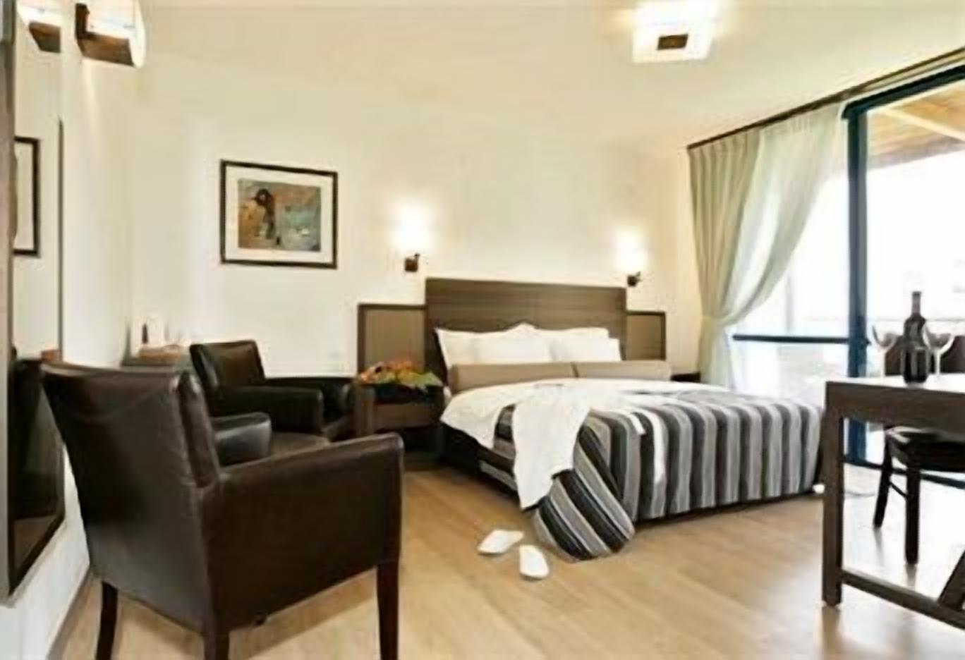 A hotel room with a bed, a desk, a chair, and a nightstand.