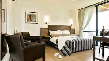 A hotel room with a bed, a desk, a chair, and a nightstand.