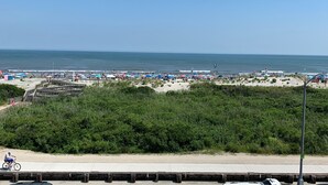 A beach with a wooden boardwalk, beach umbrellas, and a clear view of the ocean. - Roman Holiday Motel (North Wildwood)