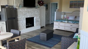 A compact living space with a stone fireplace, a bed, a dining area, and a kitchenette. - Roman Holiday Motel (North Wildwood)