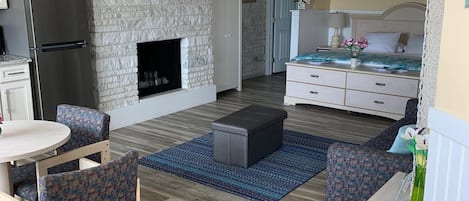Un espacio habitable compacto con chimenea de piedra, una cama, zona de comedor y kitchenette.