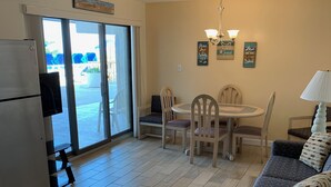 A kitchen with a refrigerator, a dining area with a table and chairs, and a sofa with cushions. - Roman Holiday Motel (North Wildwood)