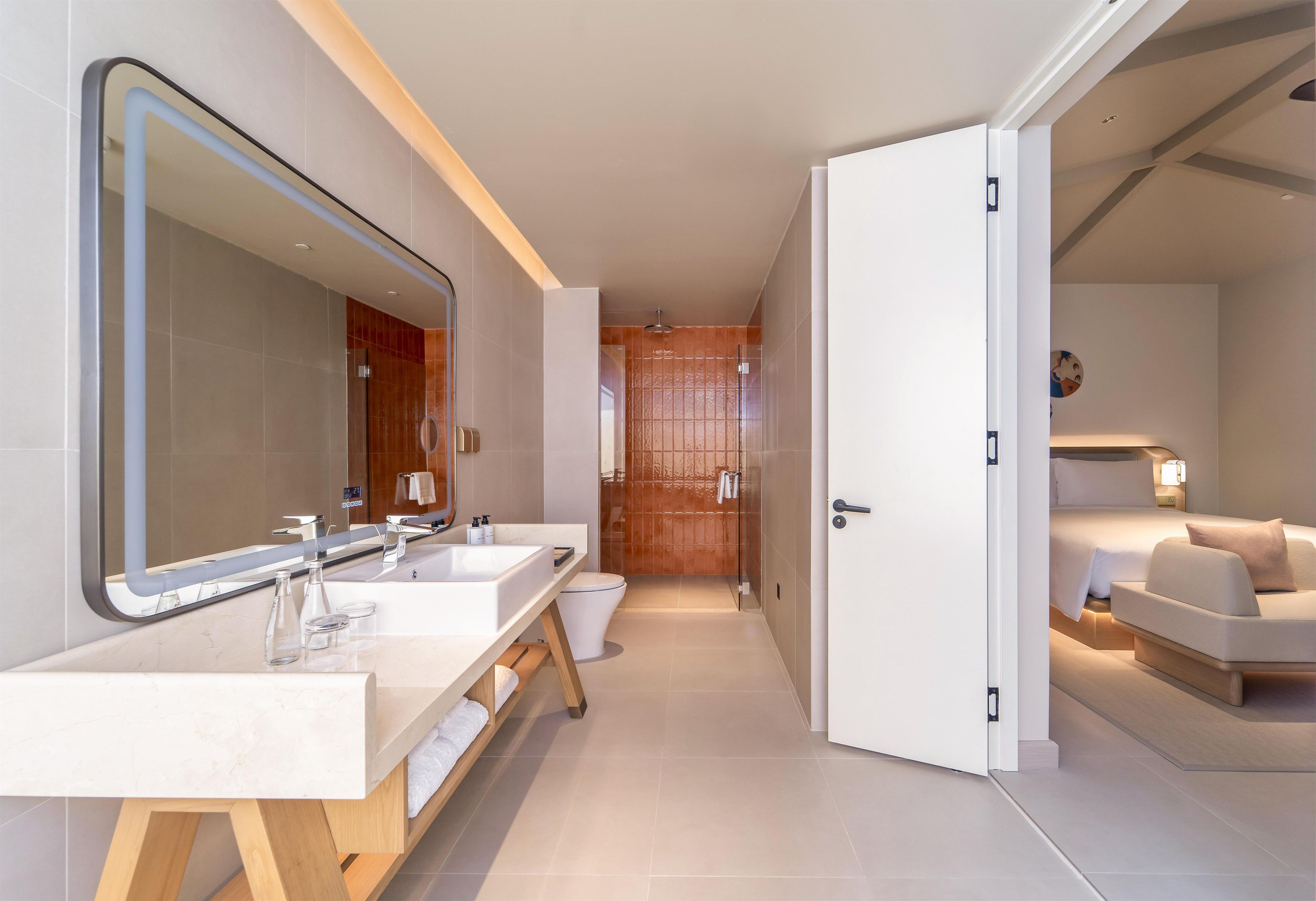Un baño moderno con lavamanos dobles, un espejo grande y una zona de ducha.
