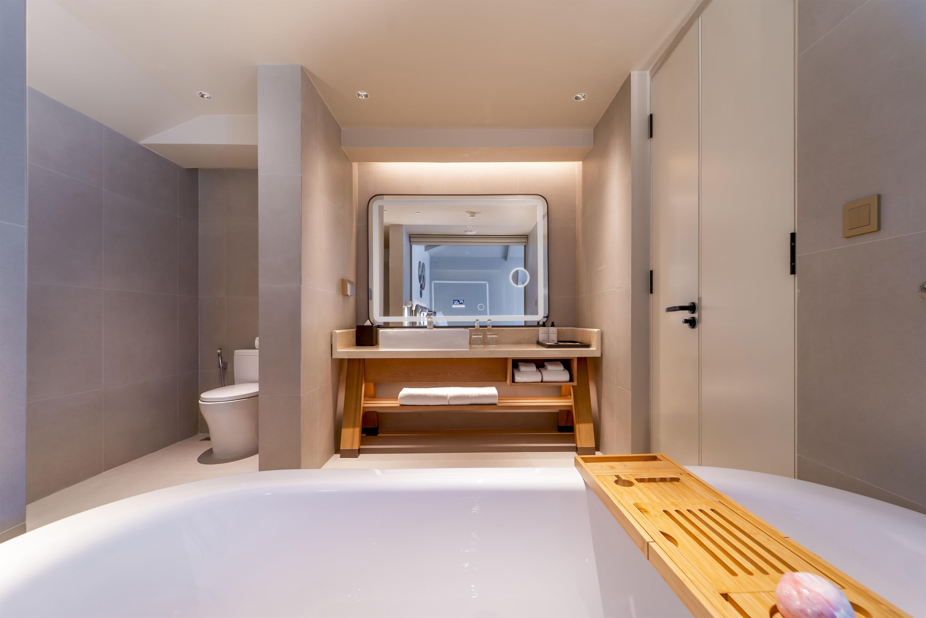 A modern bathroom with a bathtub, toilet, and vanity with a mirror.