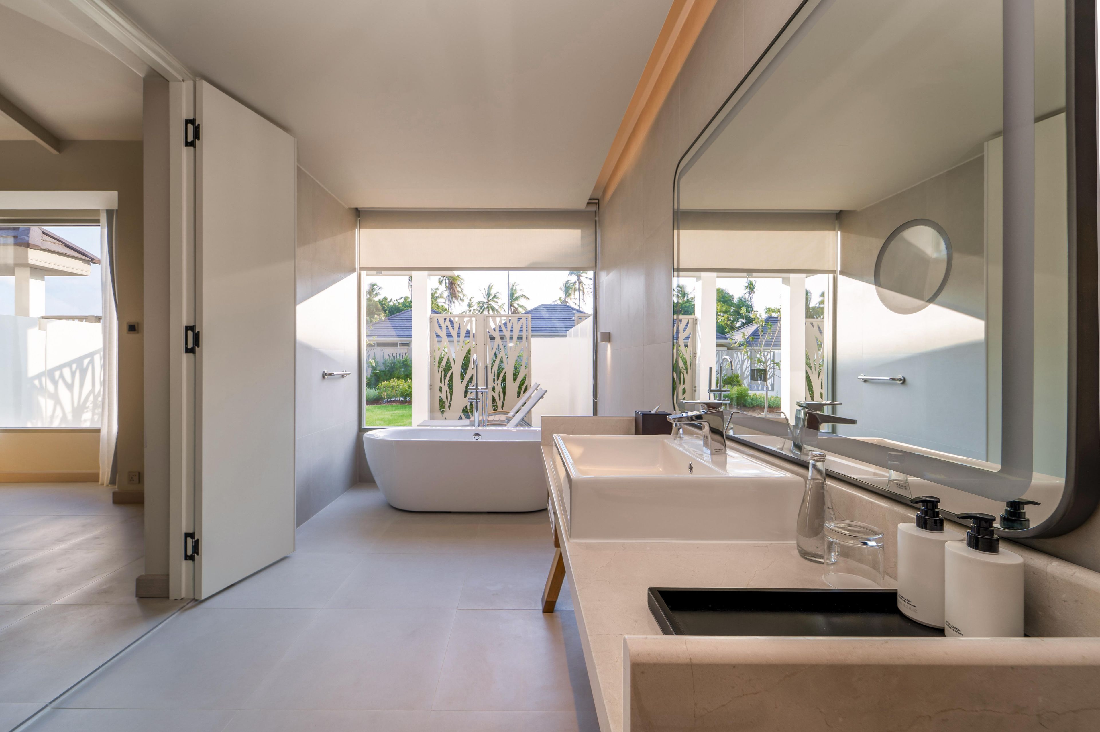 A modern bathroom with a bathtub, a large mirror, and a sink with a countertop.