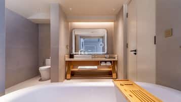 Un baño moderno con bañera, inodoro y tocador con espejo.