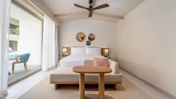 A hotel room with a bed, bedside tables, a ceiling fan, and a view of the pool area.